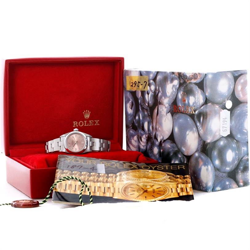 This image shows a Rolex Oyster Perpetual 76080 Women's Stainless Steel Pink Dial 76080 Women's Stainless Steel Pink Dial watch in its open red case, accompanied by brochures and tags, viewed from the front.