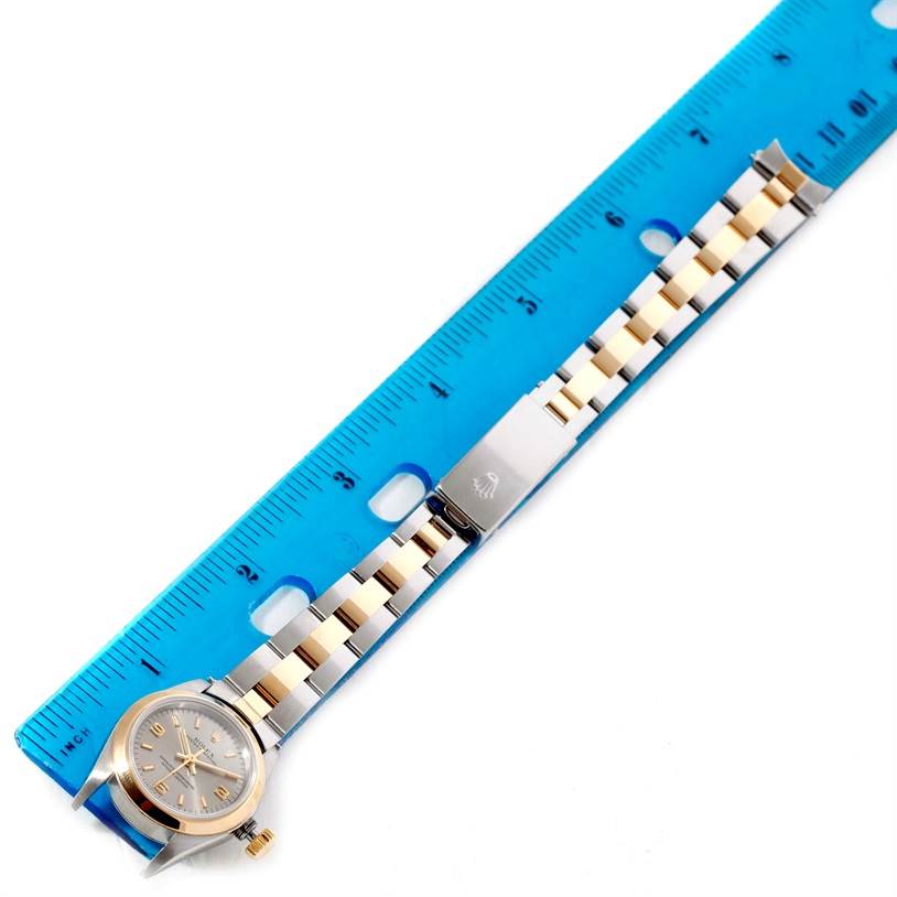 The image shows a Rolex Oyster Perpetual 67183 Women's Steel and Gold (two tone) Grey Dial 67183 Women's Steel and Gold (two tone) Grey Dial watch placed against a blue ruler, showcasing its band and watch face from a top-down angle.