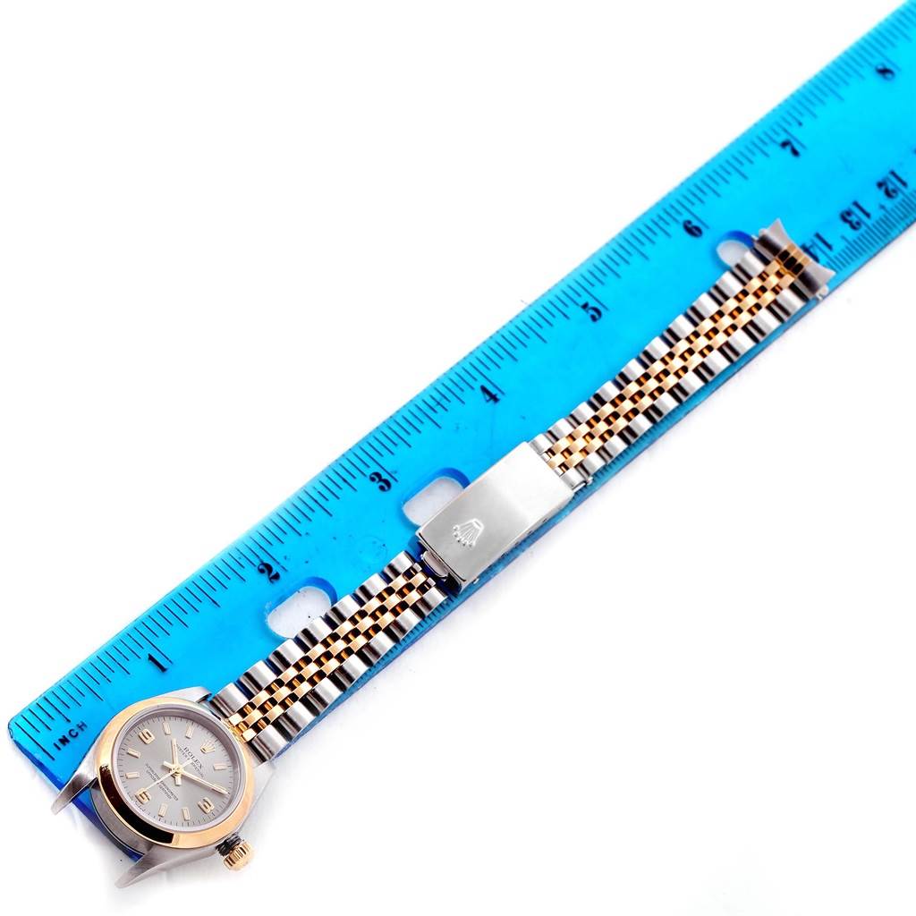 The image shows the Rolex Oyster Perpetual 76183 Women's Steel and Gold (two tone) Grey Dial 76183 Women's Steel and Gold (two tone) Grey Dial watch and its strap, measured with a blue ruler from a top-down angle.