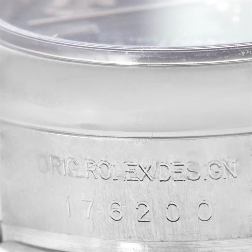 The image shows a close-up angle of the case side of a Rolex Oyster Perpetual 176200 Women's Stainless Steel Blue Dial 176200 Women's Stainless Steel Blue Dial, featuring engravings and part of the crystal.