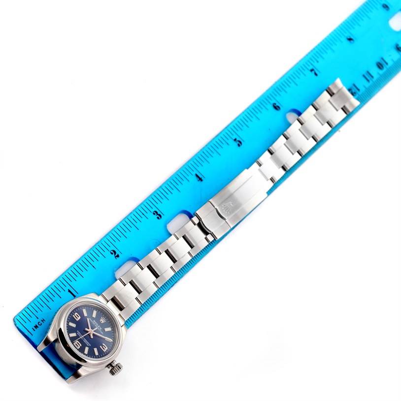 The image shows a top-down view of a Rolex Oyster Perpetual 176200 Women's Stainless Steel Blue Dial 176200 Women's Stainless Steel Blue Dial watch, highlighting its strap and clasp next to a ruler for scale.