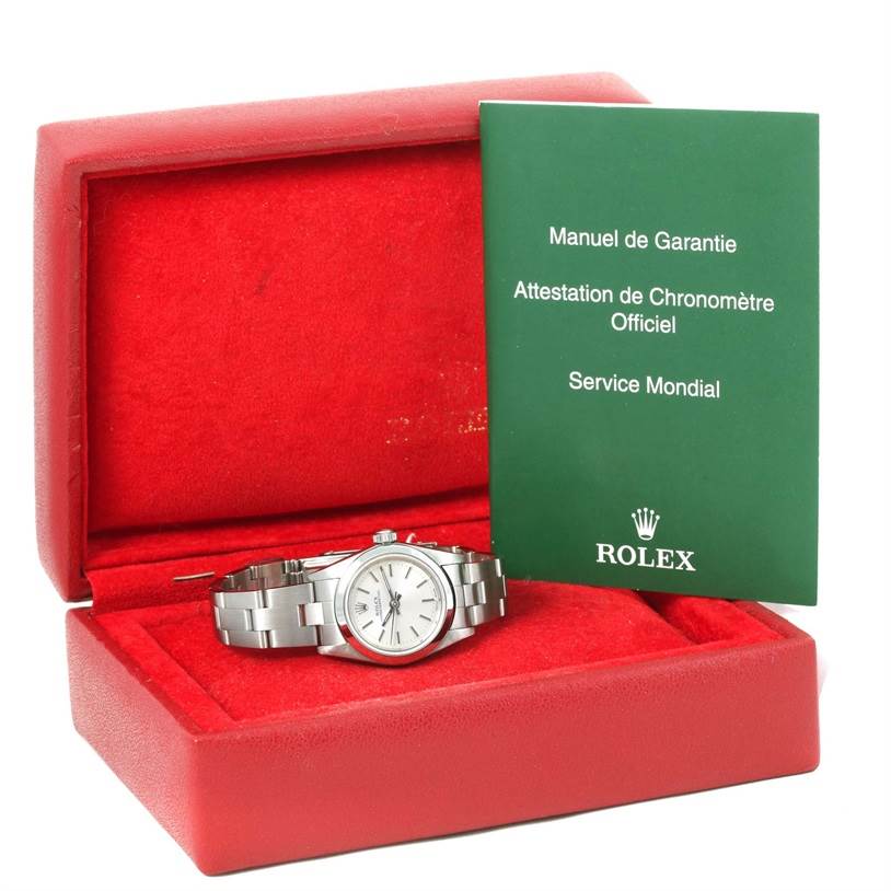 The image shows a Rolex Oyster Perpetual 76080 Women
s Stainless Steel Silver Dial 76080 Women
s Stainless Steel Silver Dial watch in its open red box, along with a green manual and warranty booklet placed upright.