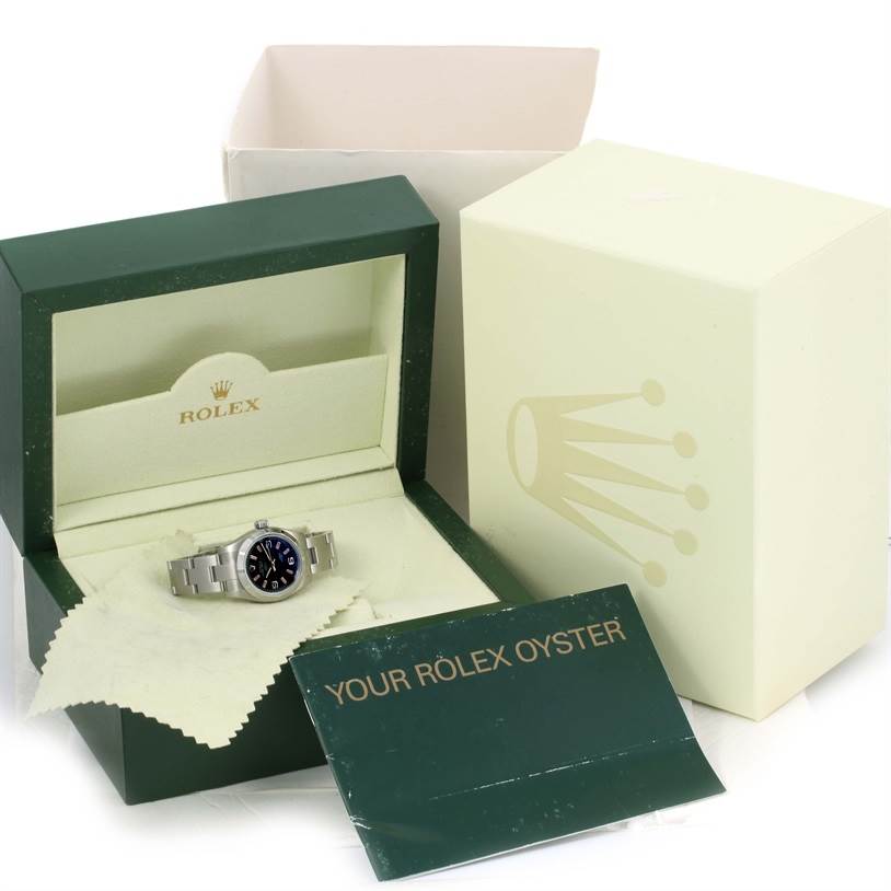 The image shows a Rolex Oyster Perpetual 176210 Women's Stainless Steel Black Dial 176210 Women's Stainless Steel Black Dial watch in its open box along with packaging and branded promotional material.