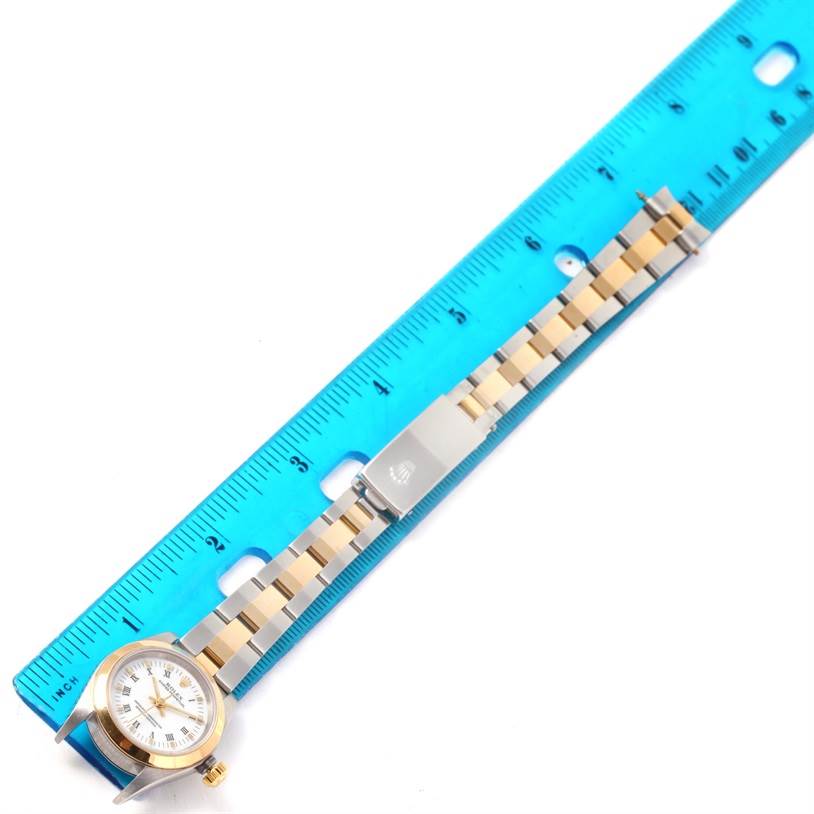 The Rolex Oyster Perpetual 76183 Women's Steel and Gold (two tone) White Dial 76183 Women's Steel and Gold (two tone) White Dial watch is shown from a top-down angle, highlighting the face, bezel, crown, and bracelet with a ruler for scale.