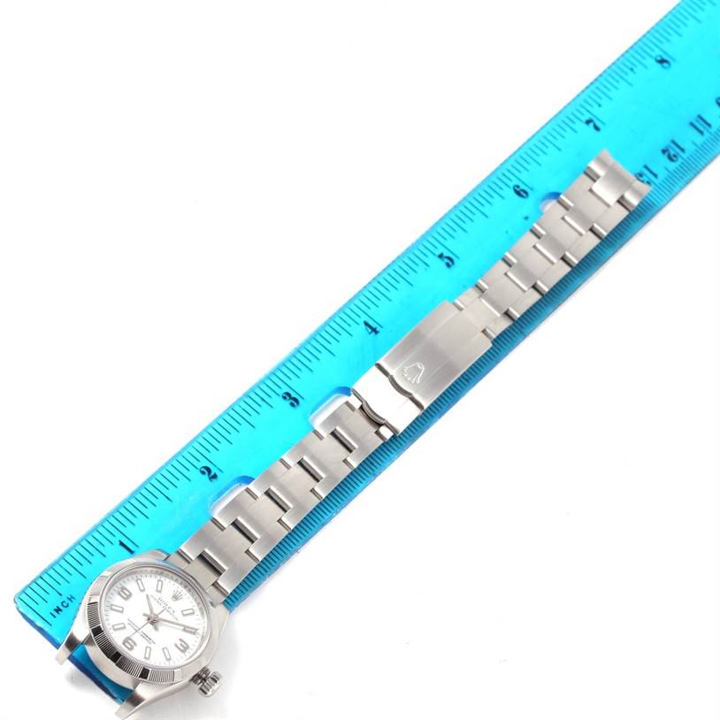 The image shows a Rolex Oyster Perpetual 176210 Women
s Stainless Steel White Dial 176210 Women
s Stainless Steel White Dial watch and band placed next to a blue ruler, viewed from overhead.