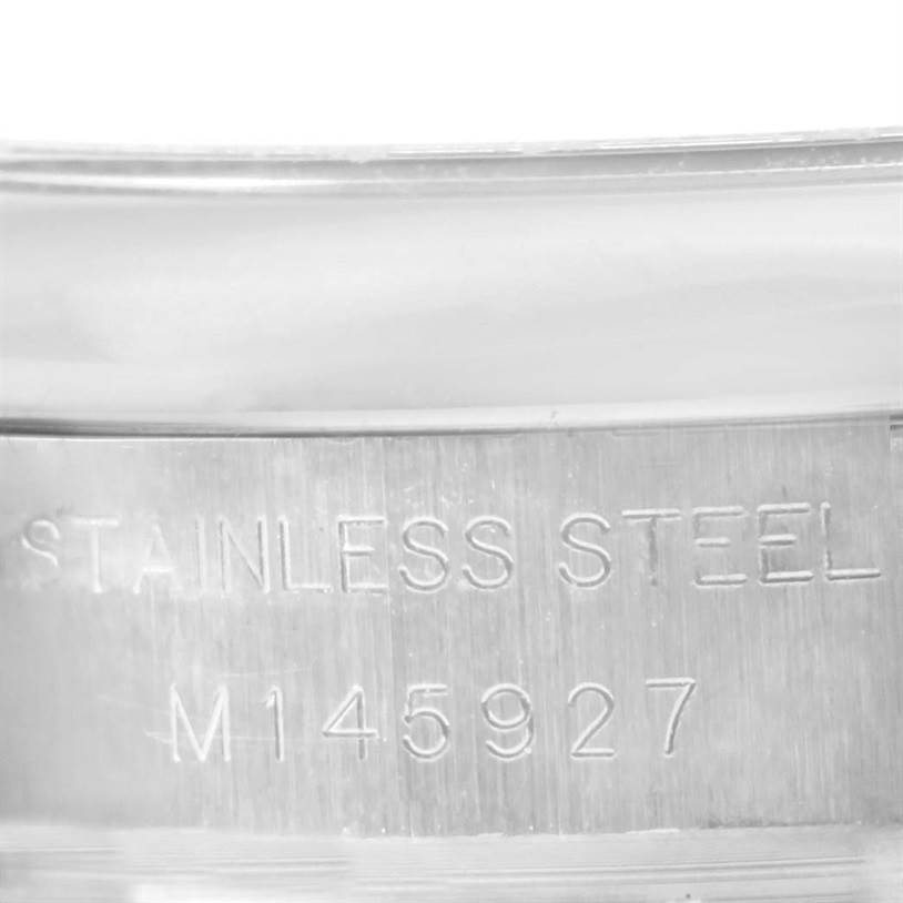 The image shows a close-up of the serial number and "STAINLESS STEEL" engraving on the Oyster Perpetual model by Rolex.