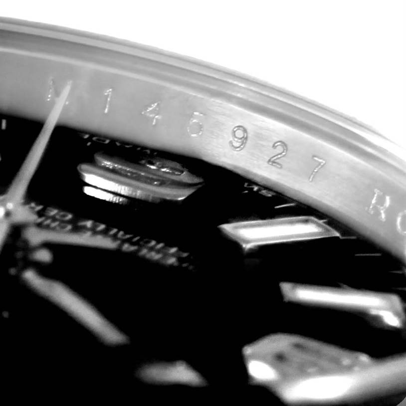 This image shows a close-up of the Rolex Oyster Perpetual 176200 Women's Stainless Steel Black Dial 176200 Women's Stainless Steel Black Dial model, focusing on the engraved serial number and part of the watch dial.