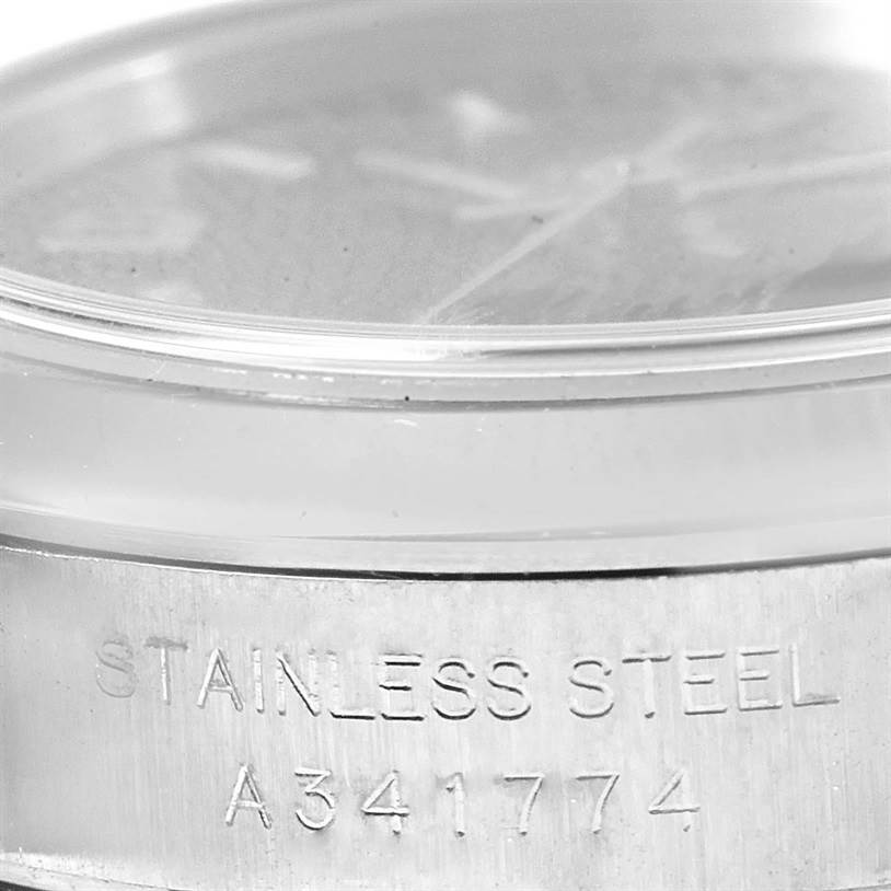 The image shows a close-up, angled view of the casing of a Rolex Oyster Perpetual 76080 Women's Stainless Steel Black Dial 76080 Women's Stainless Steel Black Dial watch, highlighting the "STAINLESS STEEL" engraving and serial number.