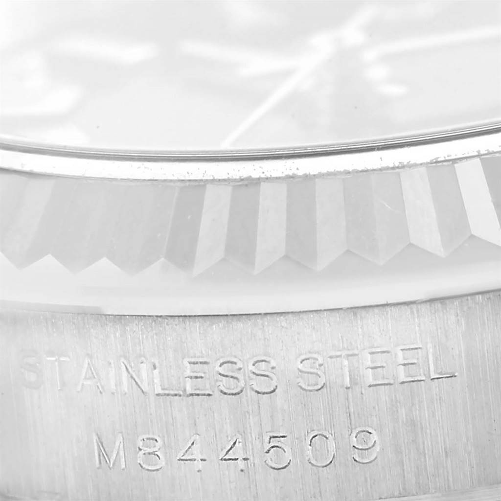 The image shows a close-up angle of the bezel and case side of an Oyster Perpetual Rolex watch, highlighting the stainless steel material and serial number.