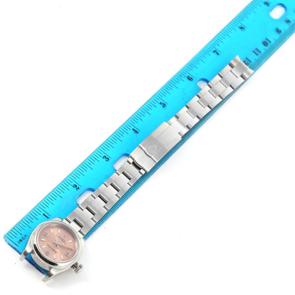 The image shows a top-down view of a Rolex Oyster Perpetual 176200 Women's Stainless Steel Pink Dial 176200 Women's Stainless Steel Pink Dial watch with its band alongside a blue ruler for measurement.