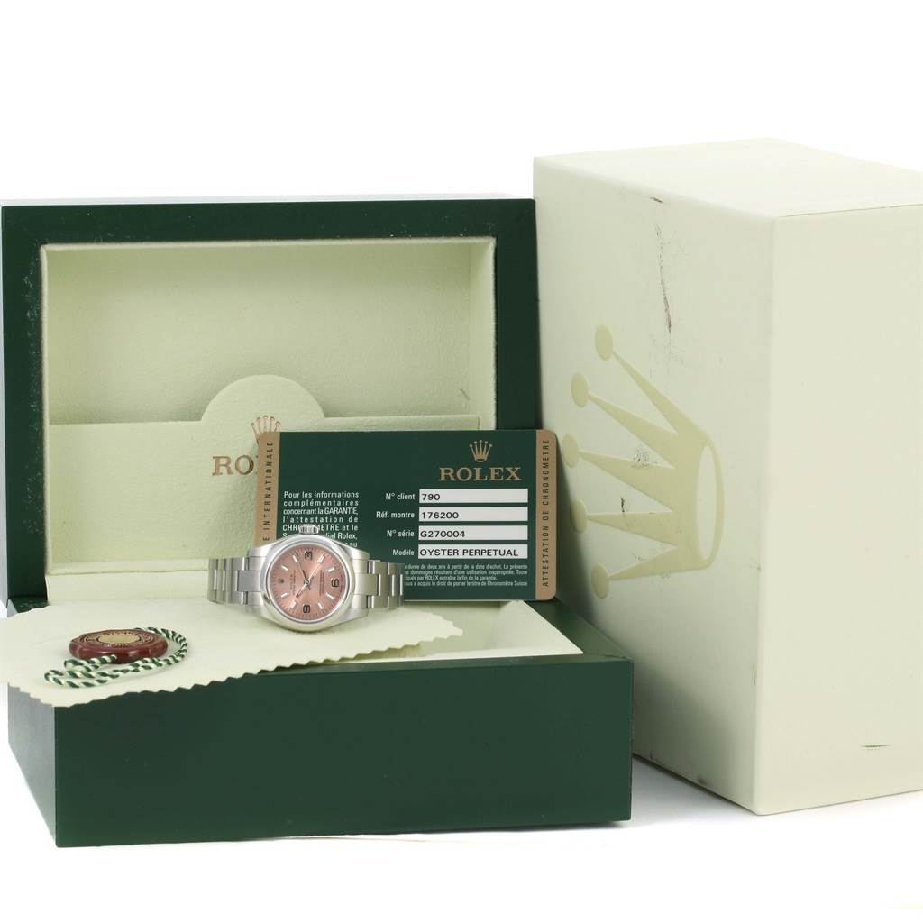 The image shows a Rolex Oyster Perpetual 176200 Women's Stainless Steel Pink Dial 176200 Women's Stainless Steel Pink Dial watch with a pink dial, displayed in its box with accompanying documentation and accessories.
