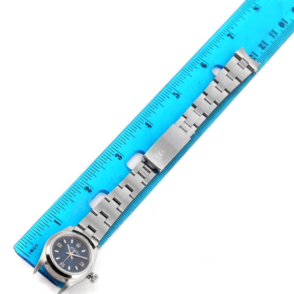 The Rolex Oyster Perpetual 76080 Women
s Stainless Steel Blue Dial 76080 Women
s Stainless Steel Blue Dial watch is shown flat with its stainless steel bracelet aligned next to a blue ruler for measurement.