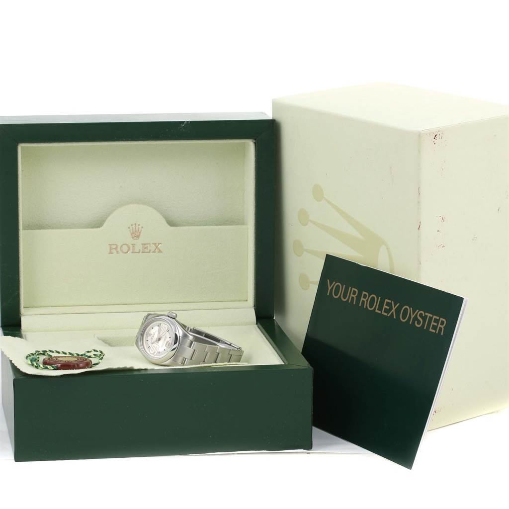 The image displays a Rolex Oyster Perpetual 176200 Women
s Stainless Steel Silver Dial 176200 Women
s Stainless Steel Silver Dial watch partially inside its box, along with its accessories and documentation.