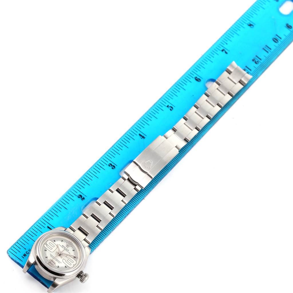 The Rolex Oyster Perpetual 176200 Women
s Stainless Steel Silver Dial 176200 Women
s Stainless Steel Silver Dial watch is shown from a top-down angle, with its full bracelet and clasp alongside a measurement ruler.