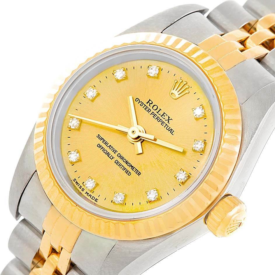 The image shows a close-up of the Rolex Oyster Perpetual 76193 Women's Steel and Gold (two tone) Champagne Dial 76193 Women's Steel and Gold (two tone) Champagne Dial watch face and part of its metal bracelet from an angled view.
