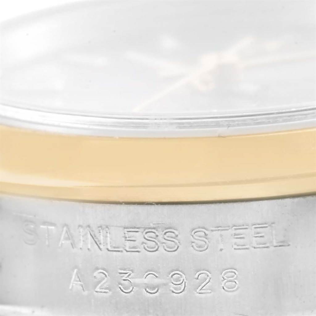 The image shows a close-up of the side of a Rolex Oyster Perpetual 76183 Women's Steel and Gold (two tone) Grey Dial 76183 Women's Steel and Gold (two tone) Grey Dial watch, highlighting its stainless steel casing and a serial number engraving.