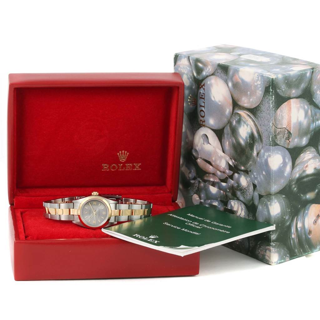 The Rolex Oyster Perpetual 76183 Women's Steel and Gold (two tone) Grey Dial 76183 Women's Steel and Gold (two tone) Grey Dial watch is displayed in an open red box with its accompanying booklet and outer decorative box.