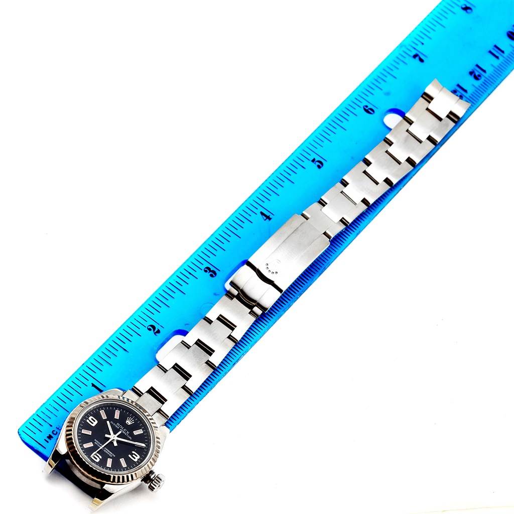 The image shows the Rolex Oyster Perpetual 176234 Women
s Stainless Steel Black Dial 176234 Women
s Stainless Steel Black Dial watch laid flat with a blue ruler measuring its length.