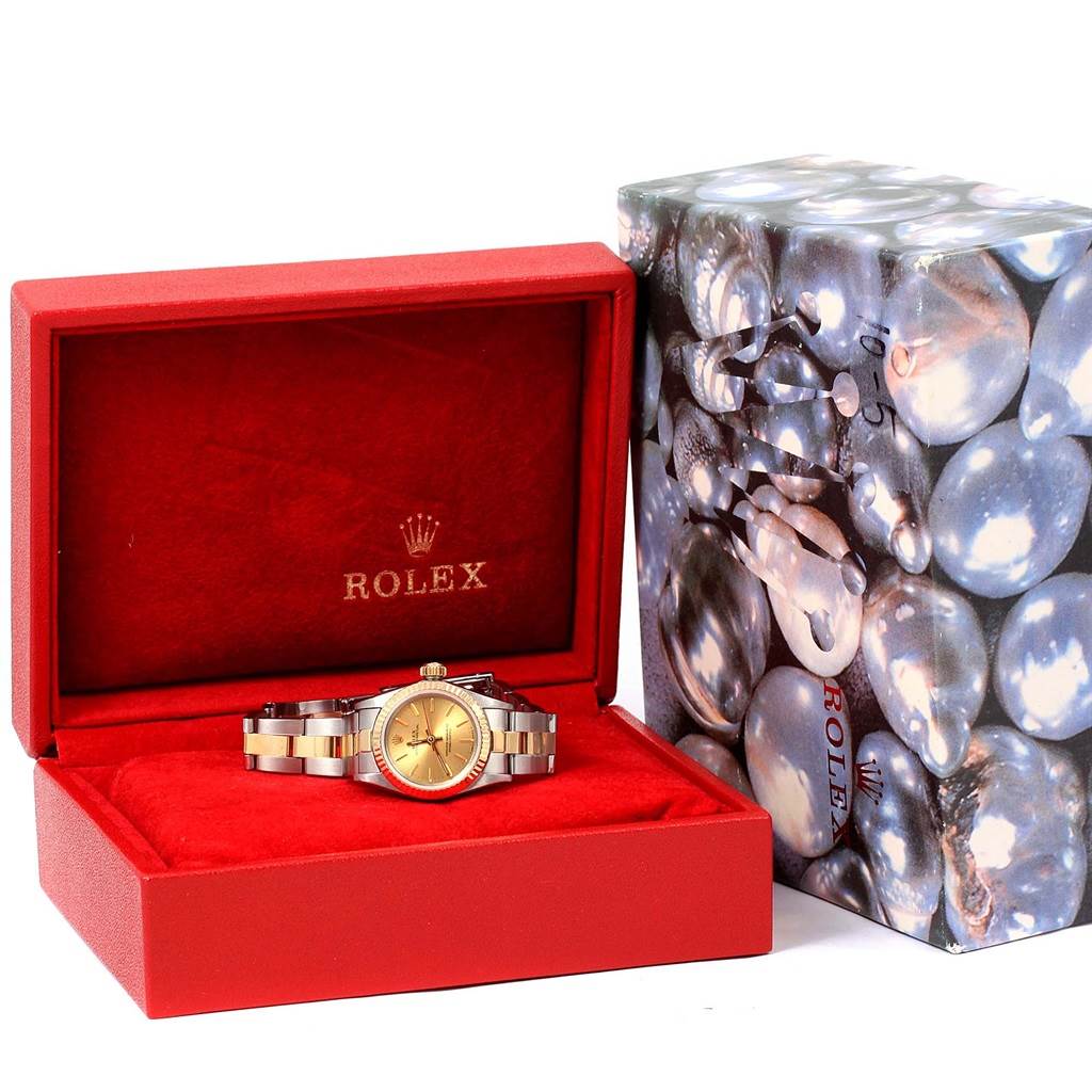 The Rolex Oyster Perpetual 67193 Women's Steel and Gold (two tone) Champagne Dial 67193 Women's Steel and Gold (two tone) Champagne Dial watch is shown in its open red box, alongside a decorative outer box.