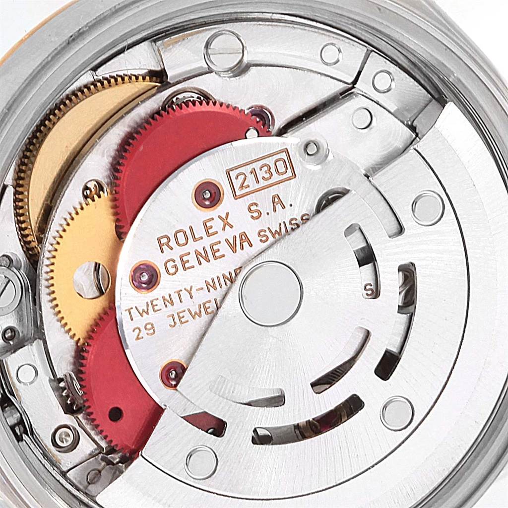 The image shows a close-up of the Rolex Oyster Perpetual 67193 Women's Steel and Gold (two tone) Champagne Dial 67193 Women's Steel and Gold (two tone) Champagne Dial watch movement, revealing the intricate gears and inner components.