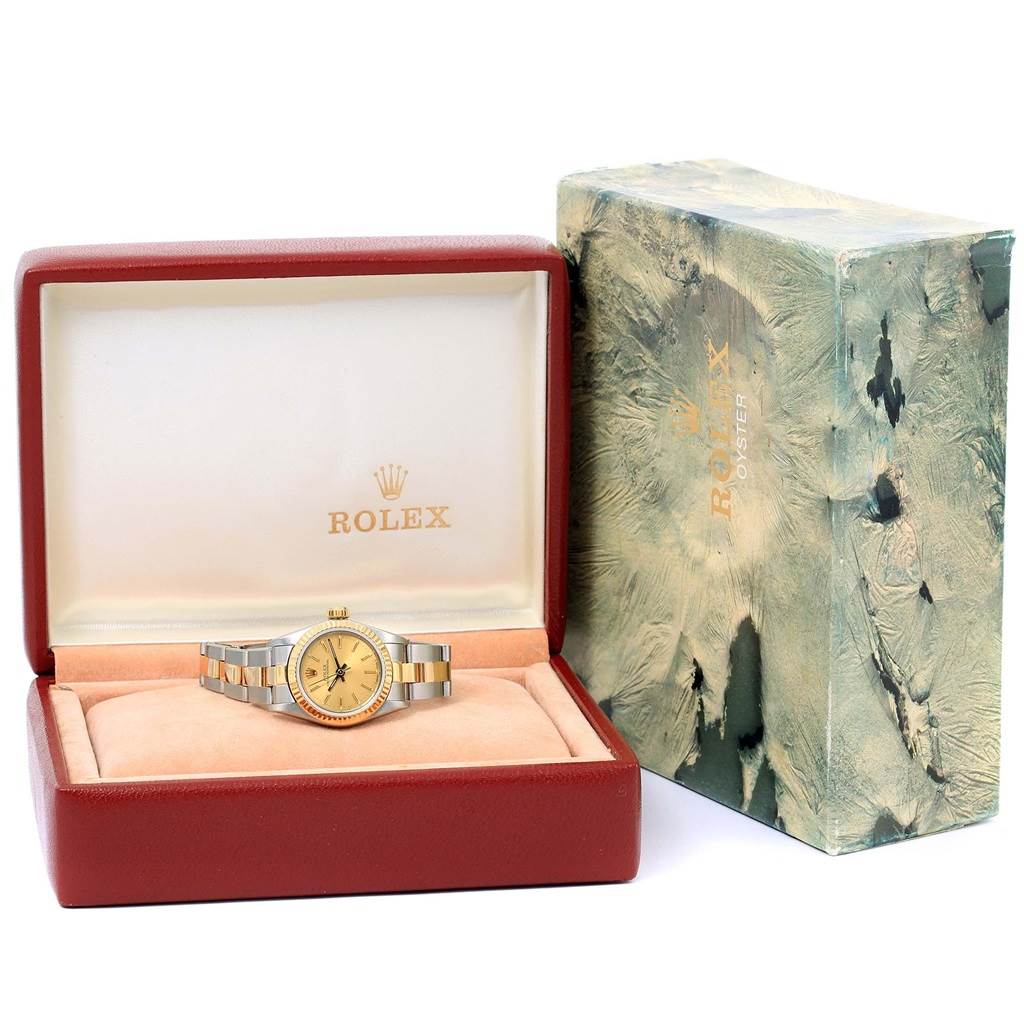 The Rolex Oyster Perpetual 67193 Women's Steel and Gold (two tone) Champagne Dial 67193 Women's Steel and Gold (two tone) Champagne Dial watch is displayed front-on, inside its branded box with a green textured outer case.