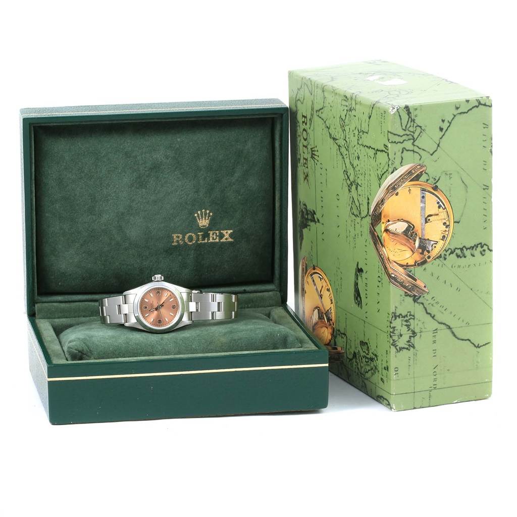 The image features a Rolex Oyster Perpetual 67180 Women
s Stainless Steel Pink Dial 67180 Women
s Stainless Steel Pink Dial watch in its green velvet case, with the outer box beside it.