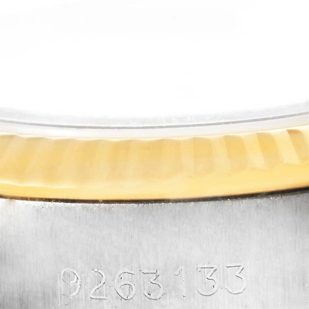 This close-up image of the Rolex Oyster Perpetual 67193 Women's Steel and Gold (two tone) White Dial 67193 Women's Steel and Gold (two tone) White Dial watch shows the edge of the fluted bezel and part of the case with an engraved serial number.