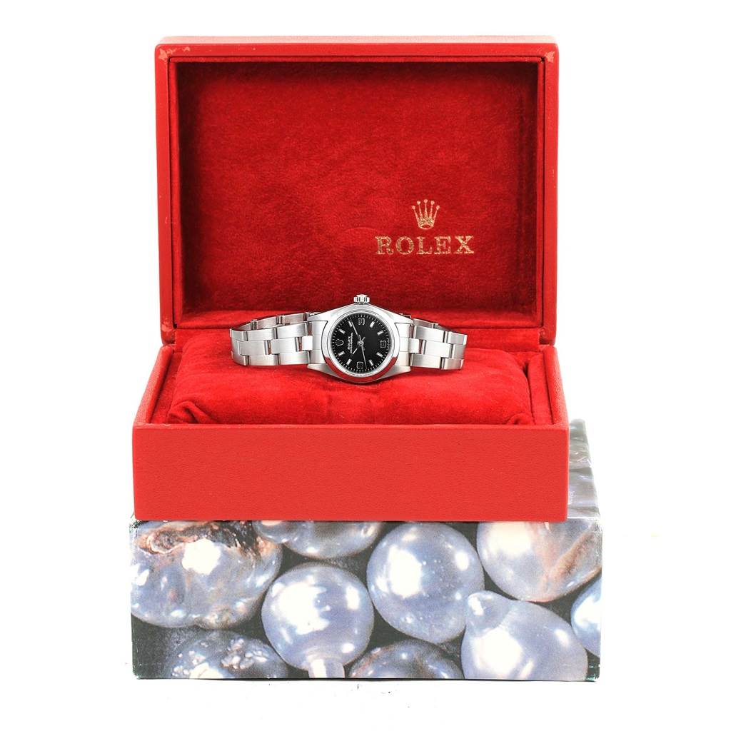 The Rolex Oyster Perpetual 76080 Women
s Stainless Steel Black Dial 76080 Women
s Stainless Steel Black Dial watch is shown from the front, displayed inside a red box with a plush red interior.