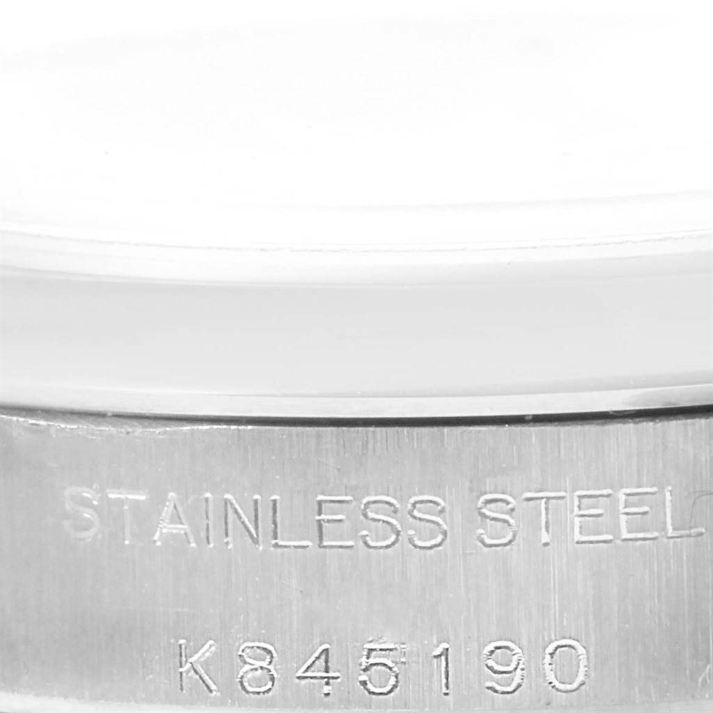 This image shows a close-up of the casing of a Rolex Oyster Perpetual 76080 Women
s Stainless Steel Black Dial 76080 Women
s Stainless Steel Black Dial watch with "STAINLESS STEEL" and a serial number engraved.