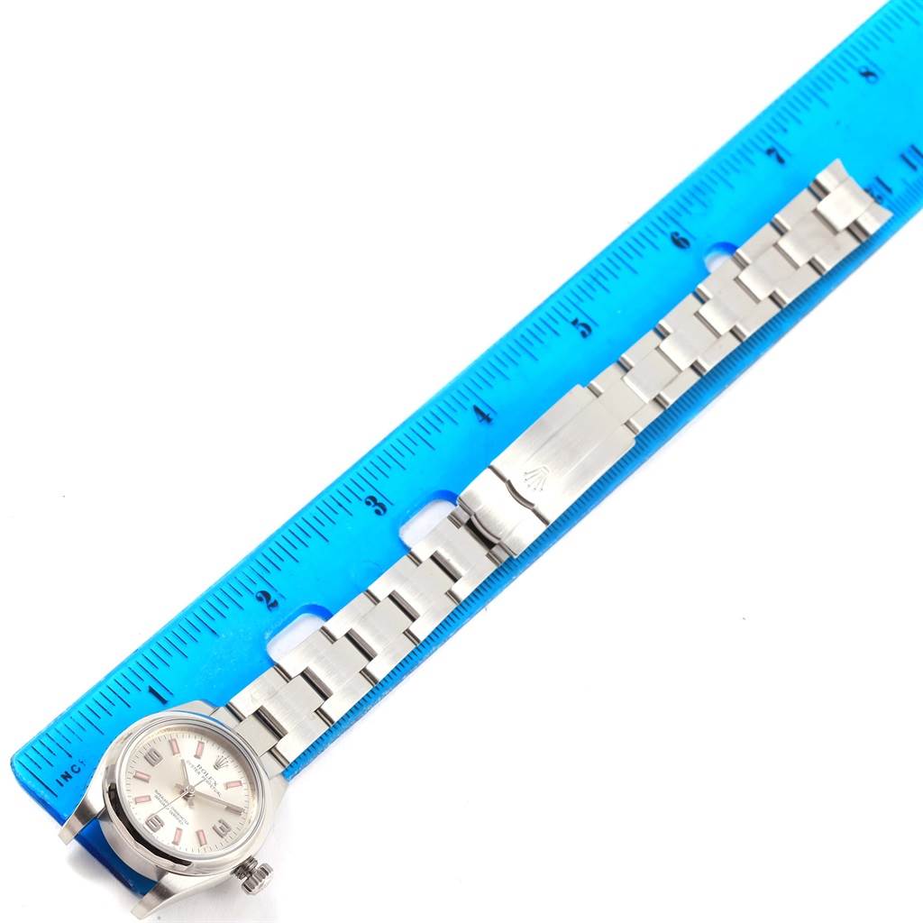 The image shows a Rolex Oyster Perpetual 176200 Women
s Stainless Steel Silver Dial 176200 Women
s Stainless Steel Silver Dial watch placed next to a ruler, displaying its face and metal bracelet from the top-down angle.