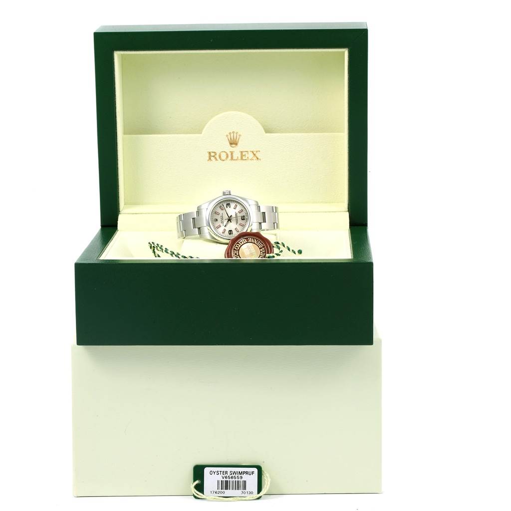 The Oyster Perpetual Rolex watch is displayed inside its open green box, showing the watch, a tag, and packaging details.