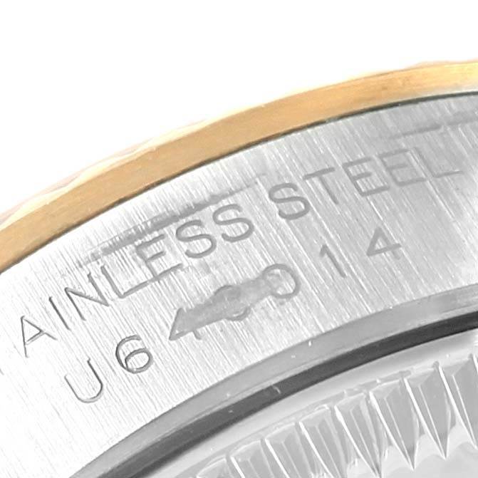 This close-up image shows a portion of the stainless steel case of a Rolex Oyster Perpetual 67193 Women's Steel and Gold (two tone) Black Dial 67193 Women's Steel and Gold (two tone) Black Dial watch, highlighting its engravings.