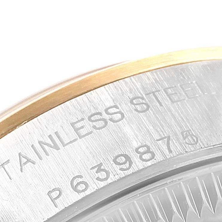The image shows a close-up of the case back and the edge of a Rolex Oyster Perpetual 76183 Women's Steel and Gold (two tone) Black Dial 76183 Women's Steel and Gold (two tone) Black Dial watch, highlighting the "Stainless Steel" engravings and serial number.