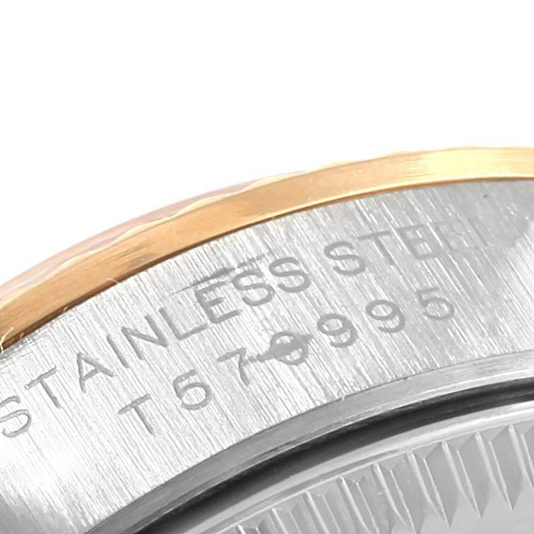 This close-up image shows the engraved case back and part of the bezel of the Rolex Oyster Perpetual 67193 Women's Steel and Gold (two tone) Black Dial 67193 Women's Steel and Gold (two tone) Black Dial model.