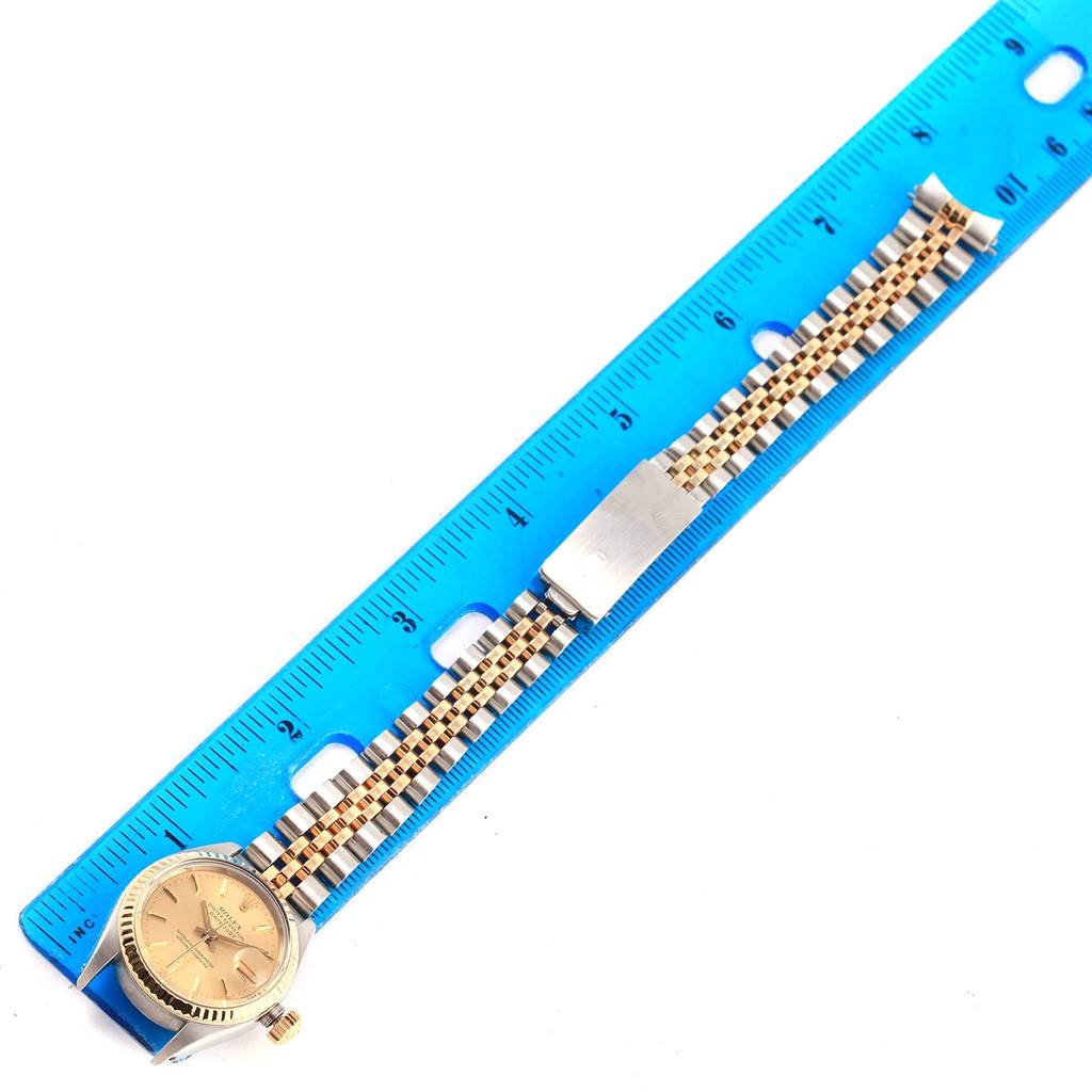 The image shows a Rolex Oyster Perpetual 6917 Women's Stainless Steel Champagne Dial 6917 Women's Stainless Steel Champagne Dial watch lying flat next to a ruler, displaying the face and bracelet.