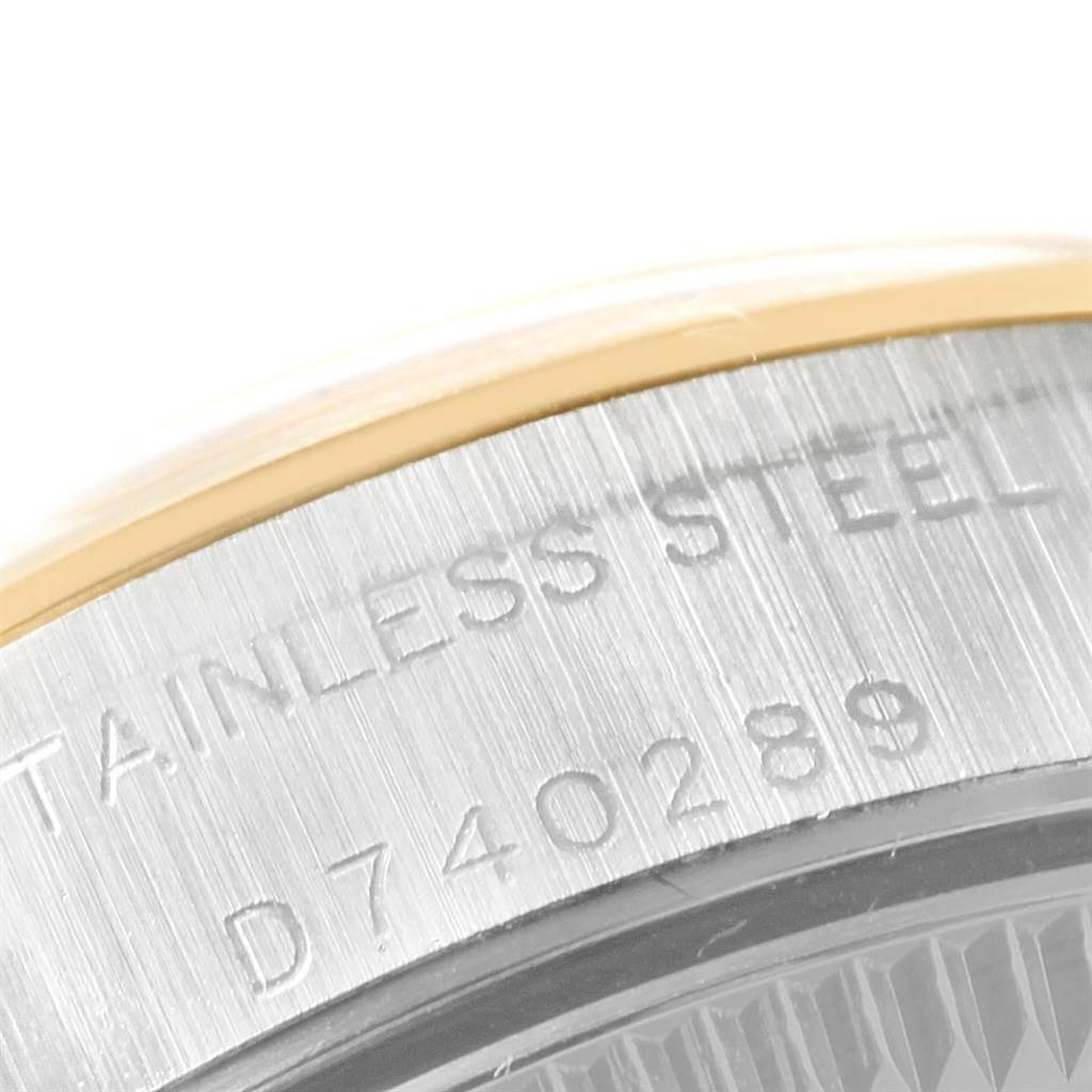 This image shows a close-up of the case back and part of the bezel of a Rolex Oyster Perpetual 76183 Women's Steel and Gold (two tone) Silver Dial 76183 Women's Steel and Gold (two tone) Silver Dial watch, highlighting its stainless steel material and serial number.