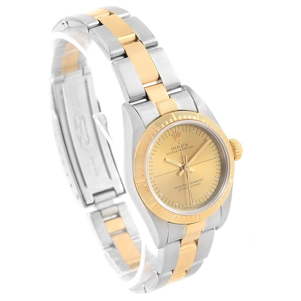 The Rolex Oyster Perpetual 76243 Women's Steel and Gold (two tone) Champagne Dial 76243 Women's Steel and Gold (two tone) Champagne Dial watch is shown at an angle displaying its gold and silver bracelet, dial, and crown.