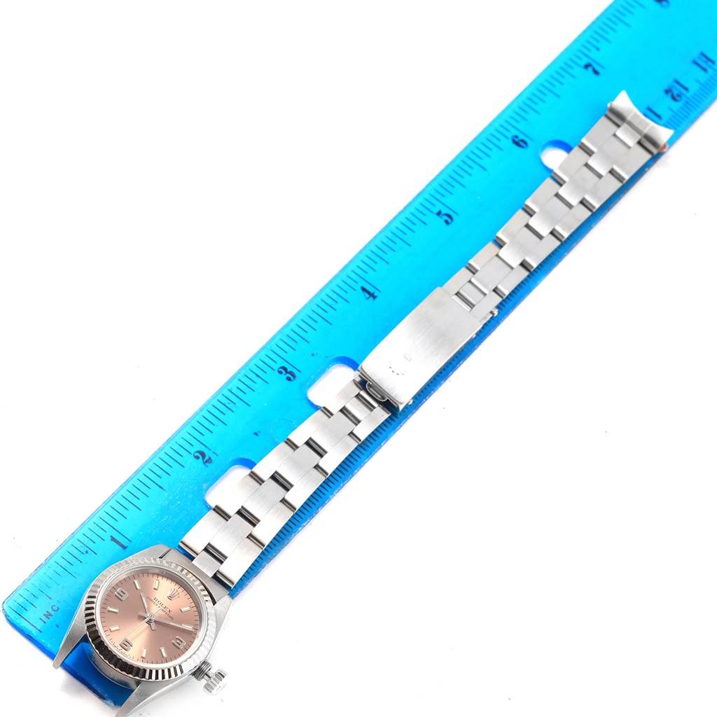 The image displays a Rolex Oyster Perpetual 67194 Women's Stainless Steel Pink Dial 67194 Women's Stainless Steel Pink Dial watch laid flat beside a blue ruler, showing its bracelet and clasp.