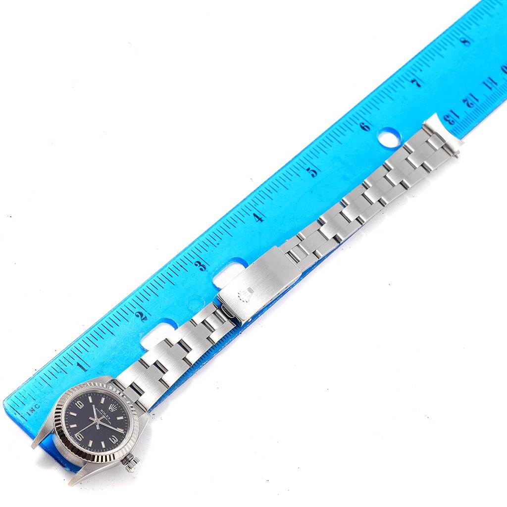 The image shows a Rolex Oyster Perpetual 76094 Women's Stainless Steel Black Dial 76094 Women's Stainless Steel Black Dial watch laid flat next to a ruler, displaying its bracelet and clasp.