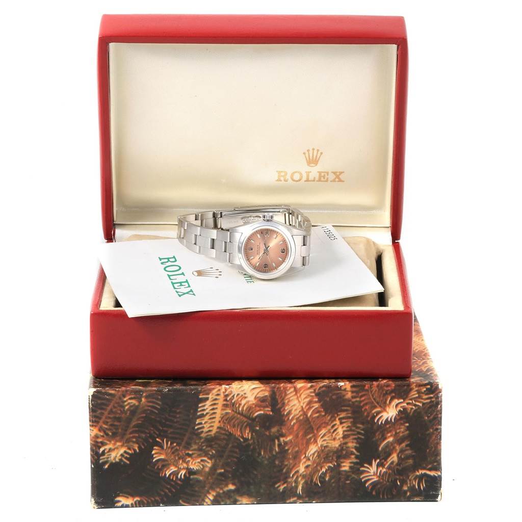 The Rolex Oyster Perpetual 67180 Women
s Stainless Steel Pink Dial 67180 Women
s Stainless Steel Pink Dial watch is shown from the front, inside its branded box, along with documentation.