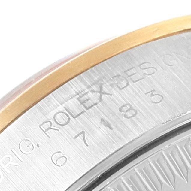 This image shows a close-up of the side of a Rolex Oyster Perpetual 67183 Women's Steel and Gold (two tone) Grey Dial 67183 Women's Steel and Gold (two tone) Grey Dial watch, specifically its bezel and engraved case.
