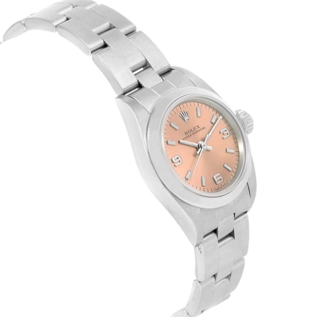 The image shows a side and front angle of a Rolex Oyster Perpetual 67180 Women
s Stainless Steel Pink Dial 67180 Women
s Stainless Steel Pink Dial watch, displaying its peach dial, bezel, crown, and stainless steel bracelet.