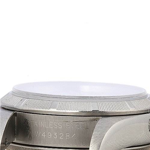 This side view of a Rolex Oyster Perpetual 67230 Women's Stainless Steel White Dial 67230 Women's Stainless Steel White Dial watch showcases the stainless steel case and part of the bezel, including serial engraving.