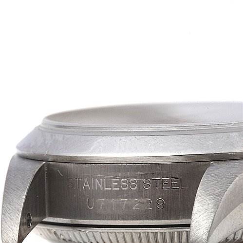 The image shows a close-up of the side of a Rolex Oyster Perpetual 67180 Women's Stainless Steel Blue Dial 67180 Women's Stainless Steel Blue Dial watch case, highlighting the "Stainless Steel" engraving and serial number.