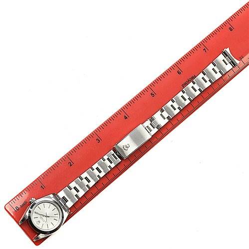 The image shows a top-down view of a Rolex Oyster Perpetual 76080 Women's Stainless Steel Silver Dial 76080 Women's Stainless Steel Silver Dial watch next to a red ruler, displaying the face and metal bracelet.