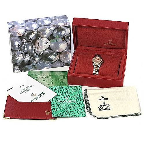 The image shows a Rolex Oyster Perpetual 76193 Women's Stainless Steel Silver Dial 76193 Women's Stainless Steel Silver Dial watch at an angle seated in its red case, surrounded by paperwork, a cleaning cloth, a wallet, and its outer box.