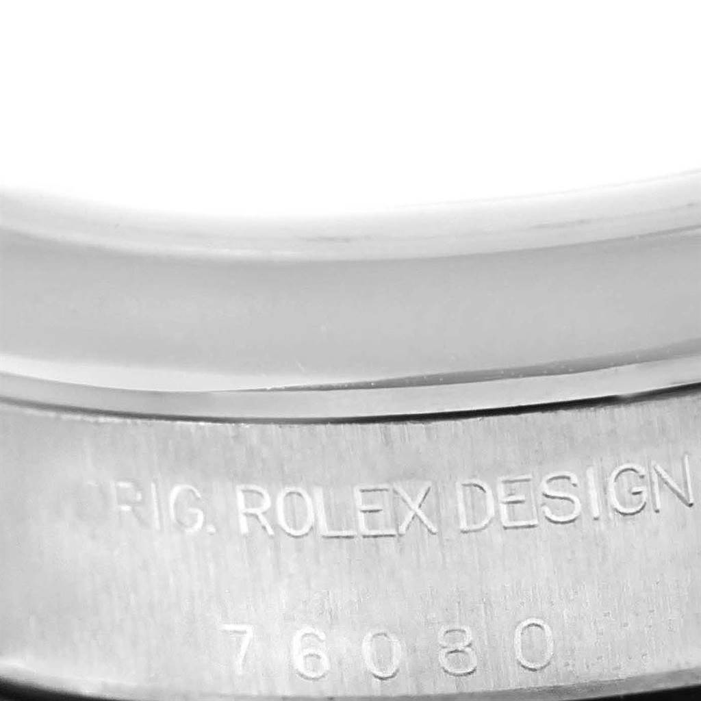 This image shows a close-up of the edge of the bezel and engraved serial number on the back case of a Rolex Oyster Perpetual 76080 Women
s Stainless Steel Silver Dial 76080 Women
s Stainless Steel Silver Dial watch.