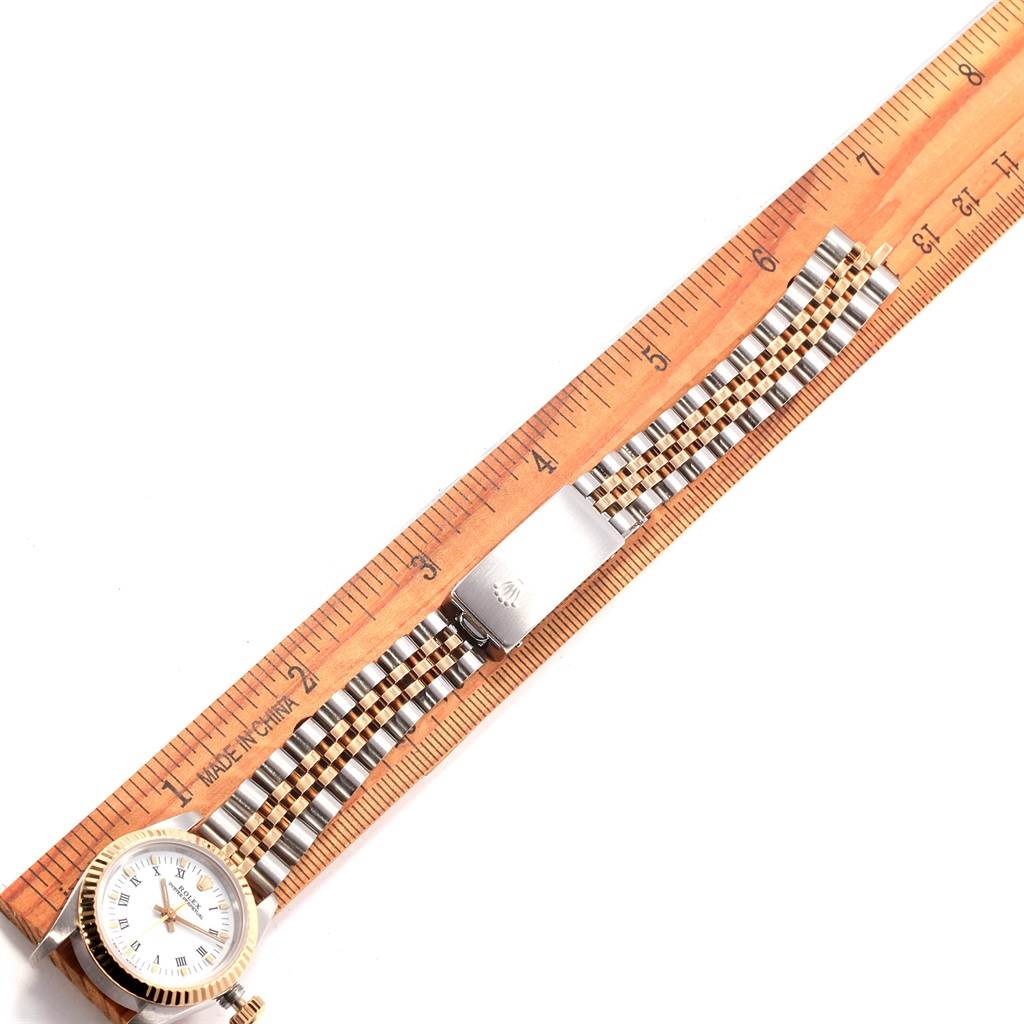 This top-down image shows the Oyster Perpetual Rolex watch with the face, strap, and clasp visible, alongside a ruler for scale.