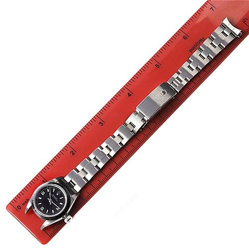 This image shows a Rolex Oyster Perpetual 67180 Women's Stainless Steel Black Dial 67180 Women's Stainless Steel Black Dial watch laid flat along a red ruler, highlighting the watch face and bracelet.