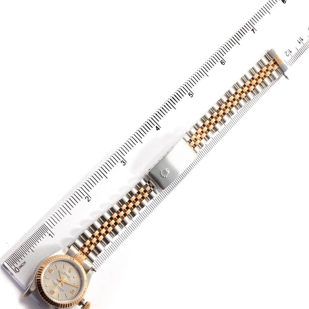 This image shows a top-down view of the Rolex Oyster Perpetual 67193 Women's Steel and Gold (two tone) Grey Dial 67193 Women's Steel and Gold (two tone) Grey Dial watch with its face and bracelet, positioned alongside a ruler.